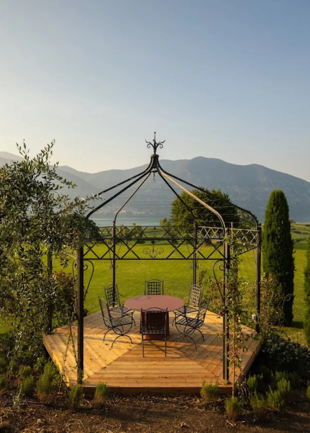 A black wrought-iron gazebo with a wooden deck and dining table - a communal space at The Candle Cluub's Retreat Cluub