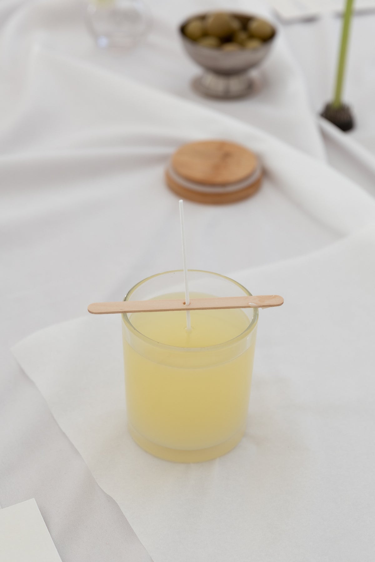 Create your candle, Workshop candle making experience with a yellow wax jar and wooden tools on a white table