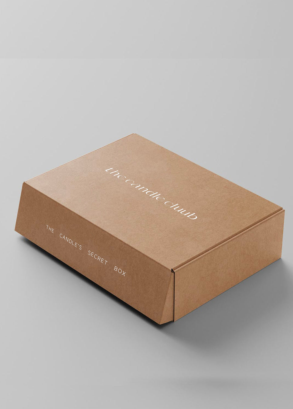 The Candle's Secret Box curated candle gift box set in kraft brown cardboard with one candle and one surprise item